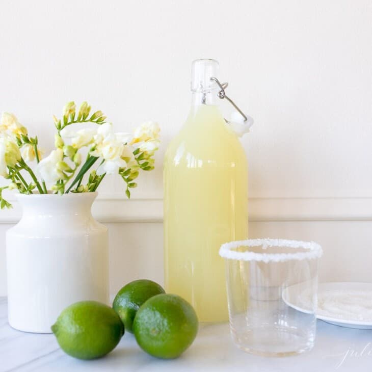 厨房白色背景,玻璃玻璃水瓶充满了自制的玛格丽塔,酸橙。万博matext登录